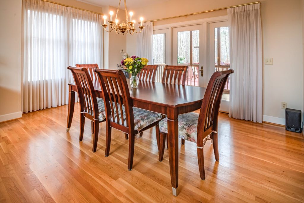 Spacious dining room showcasing wooden furniture, elegant chandelier, and natural light.